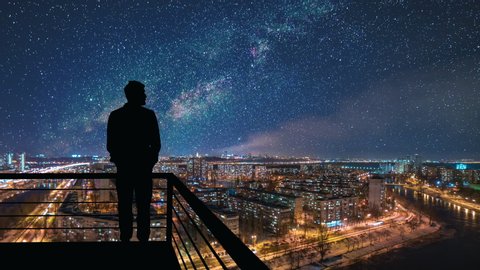 The man stands on the top of building on the starry cityscape background