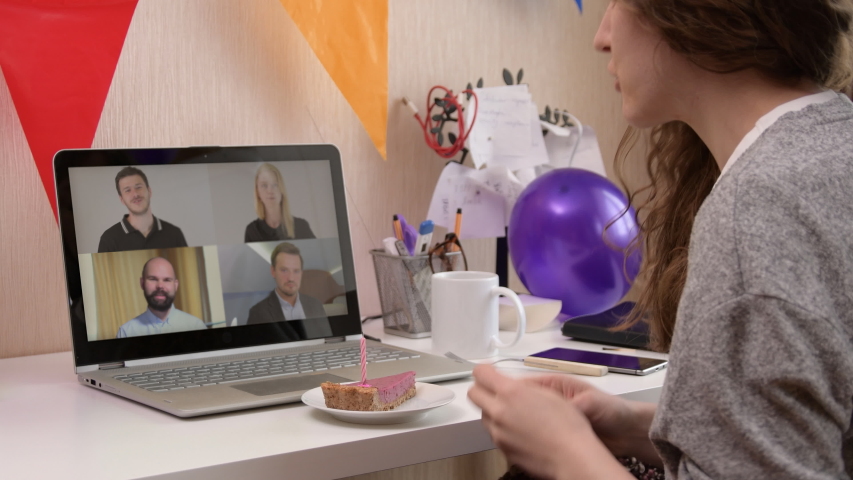 Woman celebrating her birthday through video call virtual party with friends. Lits and blows out candle. Authentic decorated home workplace. Handheld shot with gimbal. Coronavirus outbreak 2020. Royalty-Free Stock Footage #1051330468