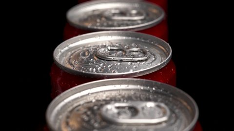 Moscow, Russia - 14 04 2020: A lot of red cans dolly footage above droplets of water on bottle. Black background. The concept of a production or can factory.