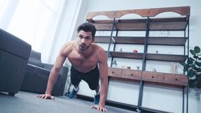 surface level view of shirtless sportsman doing push ups on floor at home