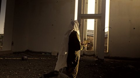 A Jewish soldier prayer With Talit and weapon on deserted building in sunset