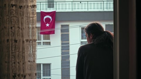 Worried millennial teen with long hair watching the empty street with Turkish flag on the background