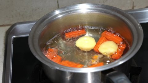 Boiling carrot and potatoes in a metal pot