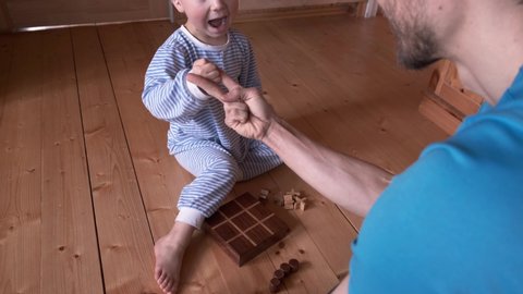 Kid and father playing board game at home. Son and dad play rock paper scissors, boy win. Parent spend time with child while quarantine and self-isolation.