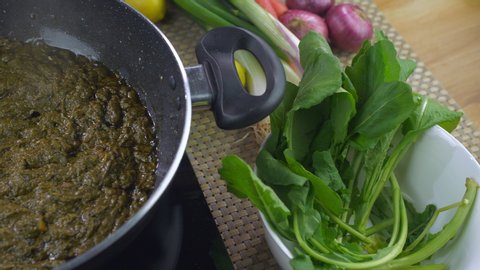 Closeup shot of woman hands adding butter in delicious Punjabi cuisine - Saag. Traditional Indian Food. Pan shot of an Indian female putting butter while cooking Sarson ka saag in a nonstick pan - ...