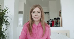 Smiling young woman working at home. Girl speaking looking at tablet talking making videochat or conference call, Happy female greeting waving hand, 4k webcam view slow motion