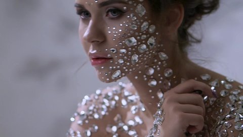 Fantastic fashion portrait of a young beautiful woman with transparent crystals on her face and shoulders. Portrait of a diamond girl, fabulous skin
