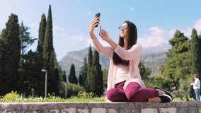 woman making live stream video on phone vlogging outdoors. Woman travel and making video call  and vlog video in park with mountains view.