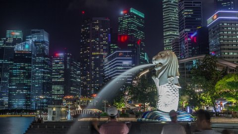 SINGAPORE - CIRCA JAN 2020: The Merlion fountain and Singapore skyline night timelapse hyperlapse. Downtown skyscrapers on a background. Merlion is an imaginary creature with a head of a lion and the