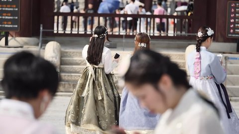Gyeongbokgung Palace, Seoul, South Korea, August/01/2019:  South Korean group of young girls dressed in traditional clothing at palace in slow motion defocused foreground