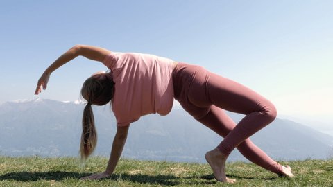 One young woman exercising yoga on mountain top in Spring. People wellbeing relaxation healthy lifestyle concept. Shot in Ticino Canton, Switzerland.
