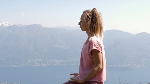 One young woman exercising yoga on mountain top in Spring. People wellbeing relaxation healthy lifestyle concept. Shot in Ticino Canton, Switzerland.
