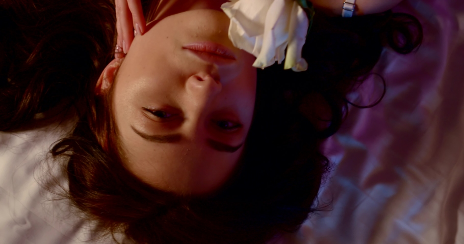 young brunette is wearing white lace bra is holding rose and luxuriate in bed