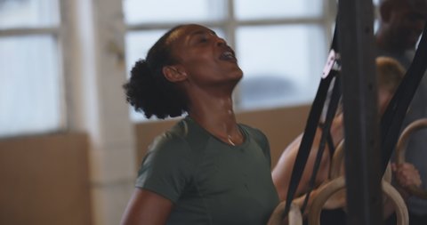 Smiling young African American woman sweating
after a working out on rings during an exercise
class at the gym