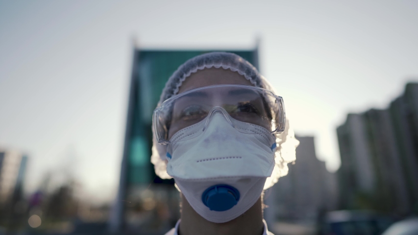 Coronavirus doctor standing in front of modern clinic building,working in the isolation ward.Medical professional in protective equipment in fight against COVID-19.Triage performing medical worker. | Shutterstock HD Video #1051369858