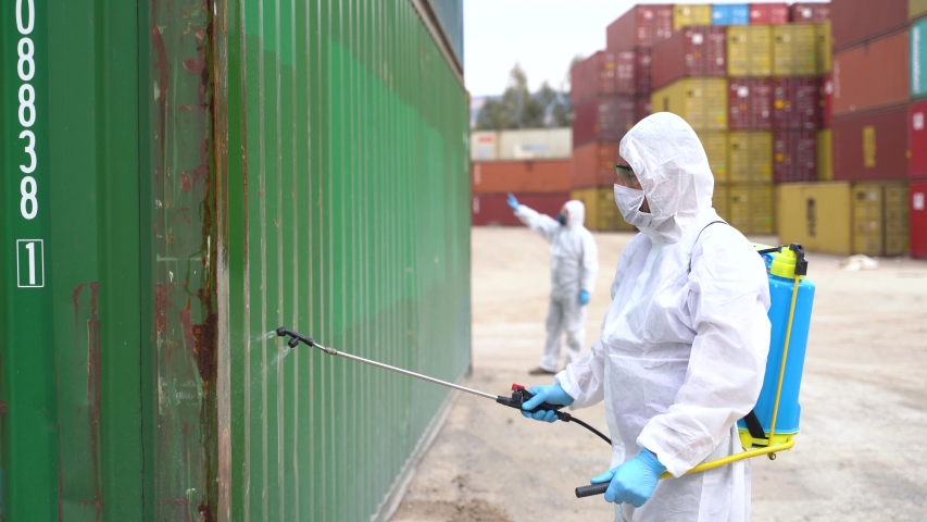 People wearing protective suits spray disinfectant chemicals on the cargo container to prevent the spreading of the coronavirus. Royalty-Free Stock Footage #1051376770