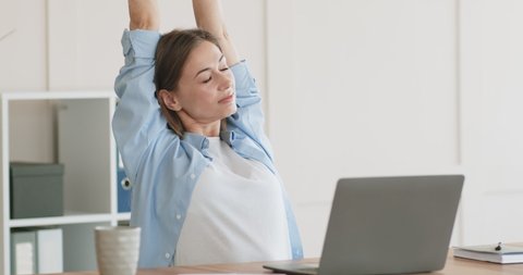 Tired of sedentary work woman stretching body at home workplace