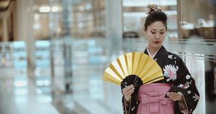 Authentic asian girl in traditional japanese geisha kimono walking in shopping mall or hotel lobby, using her smartphone - modern culture concept 4k footage