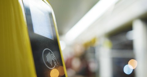 Close up of yellow bluetooth scanner of tickets in tram or bus. Woman scanning smartphone to pay for public transport. Payment by phone. Girl paying for trip.