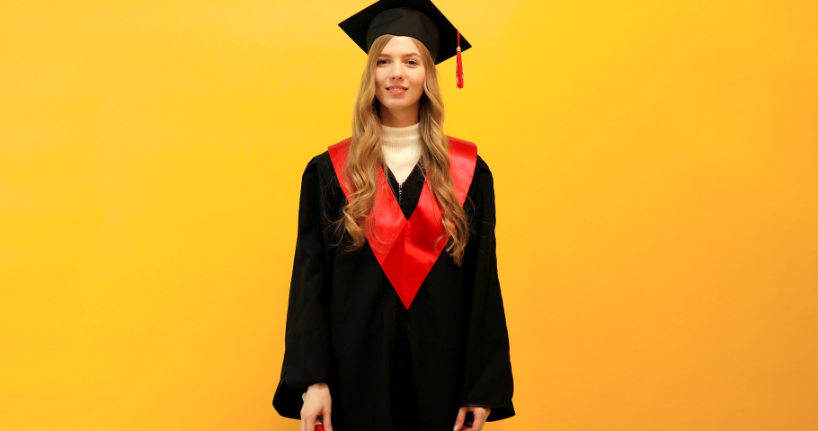 graduate girl with a diploma, shows a gesture of victory and success, on a yellow background, celebrating graduation from the University, dancing, party Royalty-Free Stock Footage #1051409677