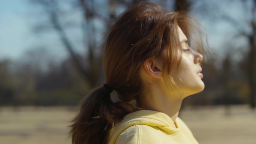 Young brunette woman doing breathing exercises in a city park.