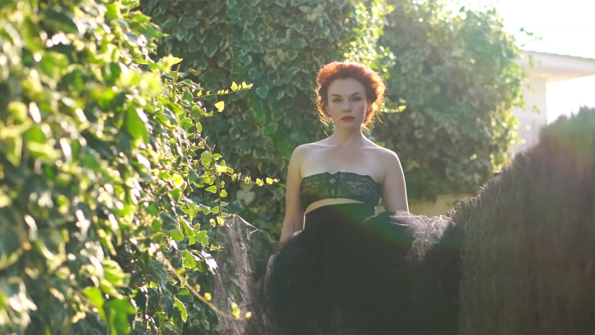 A beautiful girl with white skin and red hair in the garden on a Sunny day