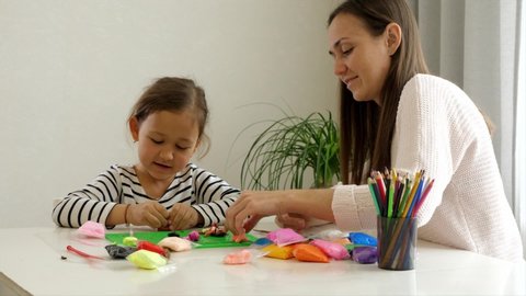 Mother and daughter is kneading modeling clay and communicating at home