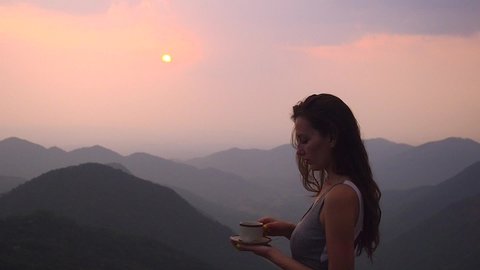 beautiful girl enjoy the organic fresh coffee or masala chai in india hills with top nice view at evening sunset