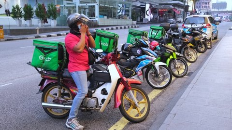 KUALA LUMPUR, MALAYSIA - APRIL 19, 2020: Food delivery service rider using motorcycle. Food delivery service through its mobile application online.