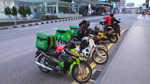 KUALA LUMPUR, MALAYSIA - APRIL 19, 2020: Food delivery service rider using motorcycle. Food delivery service through its mobile application online.