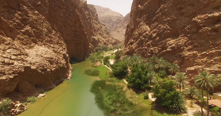 WADI SHAB, OMAN - CIRCA 2010s - An aerial view shows a waterway and greenery between canyons in Wadi Shab, Oman. Royalty-Free Stock Footage #1051445269