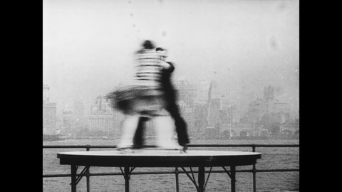 CIRCA 1930 - Earl and Inez Van Horn perform roller-blading stunts together in Governor's Island with the New York City skyline in the background.
