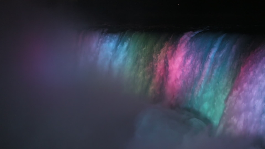 NIAGARA FALLS, NEW YORK - 8 AUG 2019: Niagara Falls night water multi colored lights waterfall Slow. International border USA New York and Canadian province Ontario. honeymoon vacation destination.