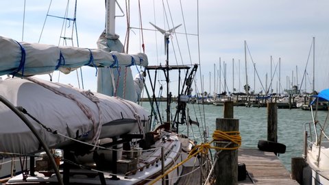Sailboat tied to the dock in a marina in Rockport, Texas, in close up of rigging, with gentle motion of the boat as it bobs and floats on the water.