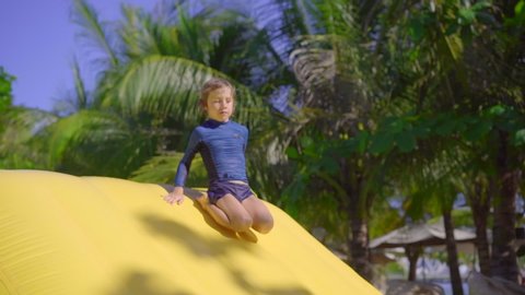 Little boy on an inflatable obstacle course in an aqua park. Summer concept. Slowmotion shot