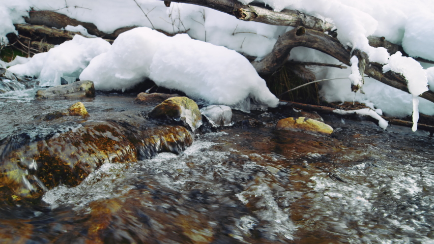 Moving upstream in snowy frigid river in Utah Wasatch Mountains slow motion