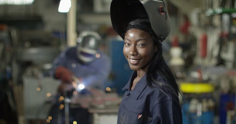 4K Portrait beautiful smiling female welder in metalwork shop. Slow motion.