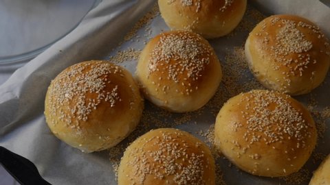 Burger rolls are fresh from the oven, still hot, generously sprinkled with sesame seeds. Homemade round-shaped pork buns, spotted to ruddy crust