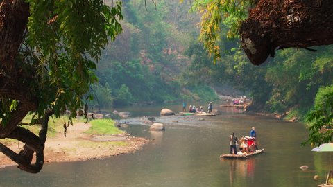 CHIANG MAI / THAILAND - JAN 12,2020: Active lifestyle travelers enjoy trekking on elephant and river rafting on bamboo rafts in a national park Maetaman Elephant Camp amid beautiful nature in Asia