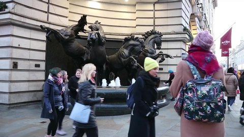 London, UK-January 2020: Crowd of people walking in front of " The Horses of Helios", also known as "The Four Bronze Horses of Helios". Bronze sculpture of four horses. Near Piccadilly Circus Station.
