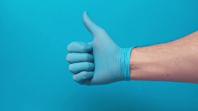 male hand in latex glove with thumb up isolated on blue, covid-19 concept