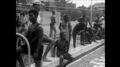 CIRCA 1945 - African-American city youth enjoy swimming and diving at a municipal pool.