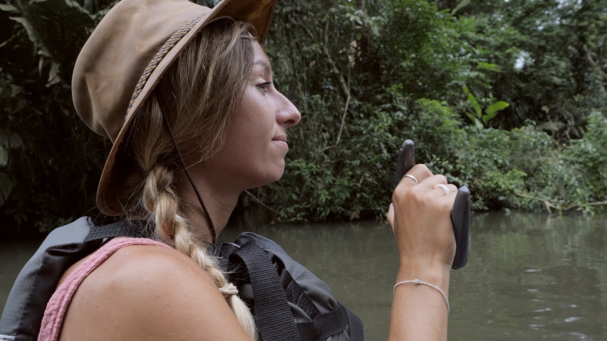 Tortuguero Costa Rica rainforest, young woman roaring on green canoe exploring the Tortuguero canal national park, wildlife and nature reserve. Slow motion 