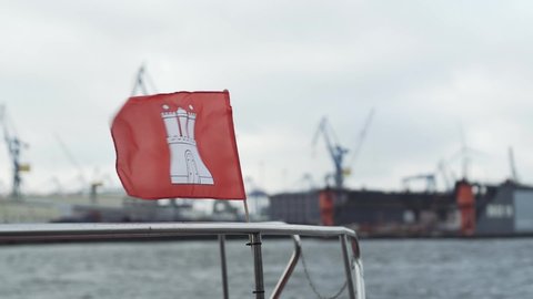 Flag of city of Hamburg fluttering slowmotion in the strong wind at the river in Hamburg, Germany.