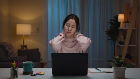 Portrait of asian woman and serious millennial hard working at home pain with office syndome. Working from Home overload at night, self isolation in next normal concept.Working late and Overtime