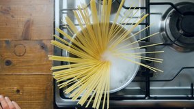 Top view on silver pot of boiling water on kitchen stove. Female chef adds authentic italian spaghetti pasta in symmetric and professional way. Cooking at home, food or cook blog - Powered by Shutterstock - Get 15% off with code: PIKWIZARD15