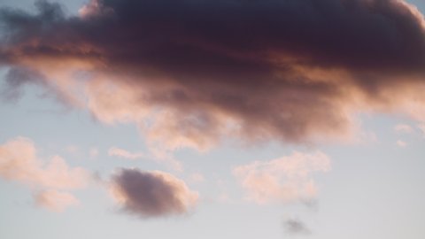 Dramatic blue sky with pink fluffy clouds turning orange then darker. Gathering dark clouds of apocalypse. Slow motion b roll. Timelapse cloudscape. Beautiful concept of brighter days ahead