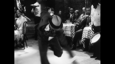 CIRCA 1920 - Bessie Smith drinks at the bar of a speakeasy while others dance to the house band.
