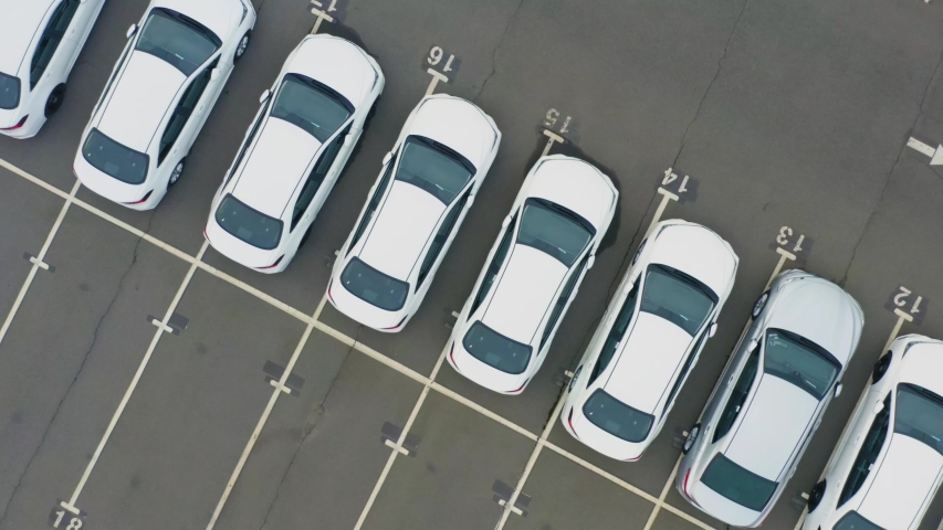 Aerial top down view of the dealership or customs terminal parking lot with a rows of new passenger cars Royalty-Free Stock Footage #1051506400