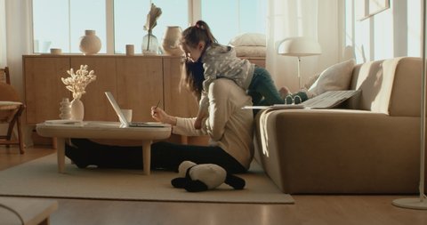 Mother working from home, having a phone call, while her daughter distracts her and drawing attention. Shot on RED Dragon
